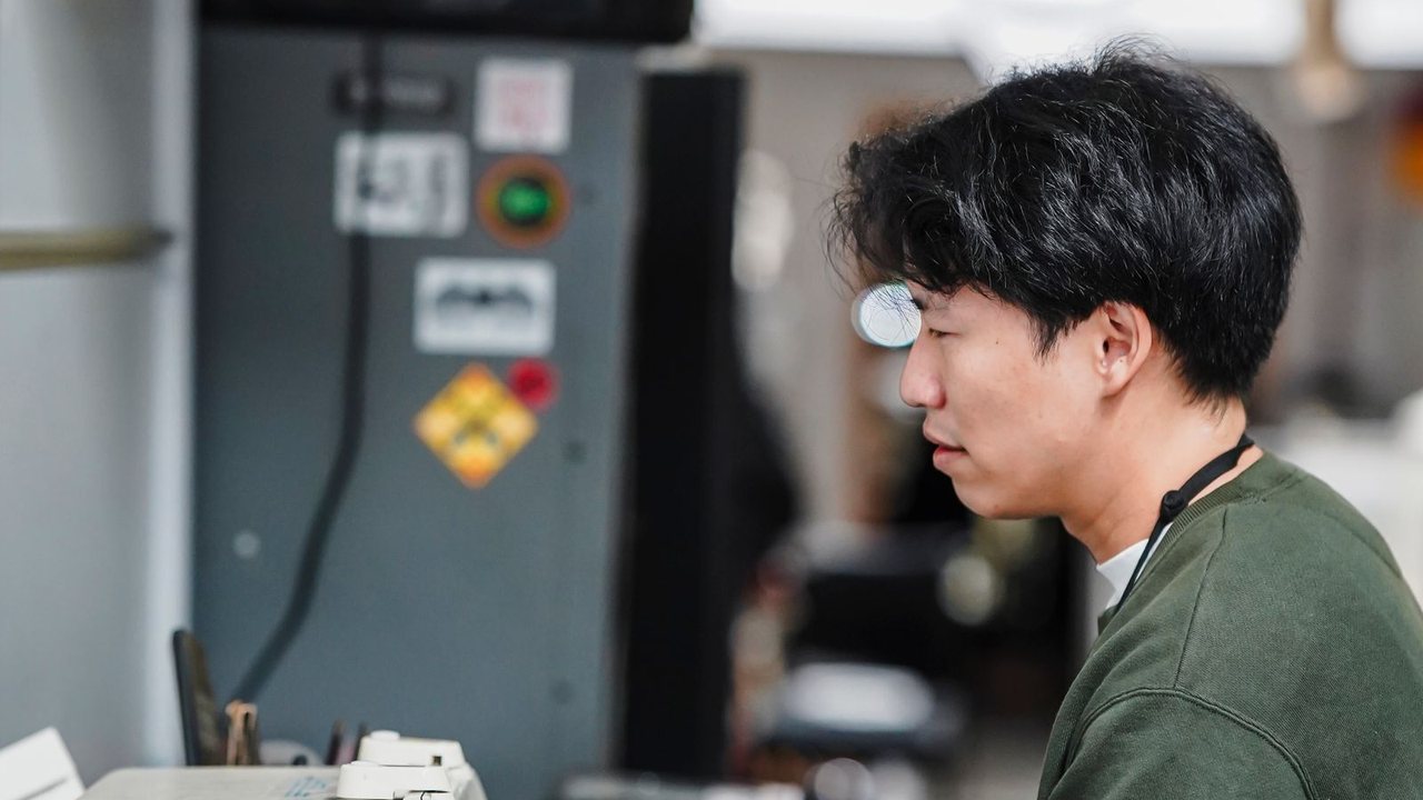 工場で、機械を操作している作業員の横顔